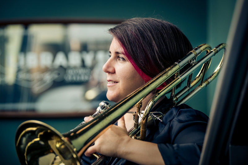 Woman looking into the distance, holding a trombone.